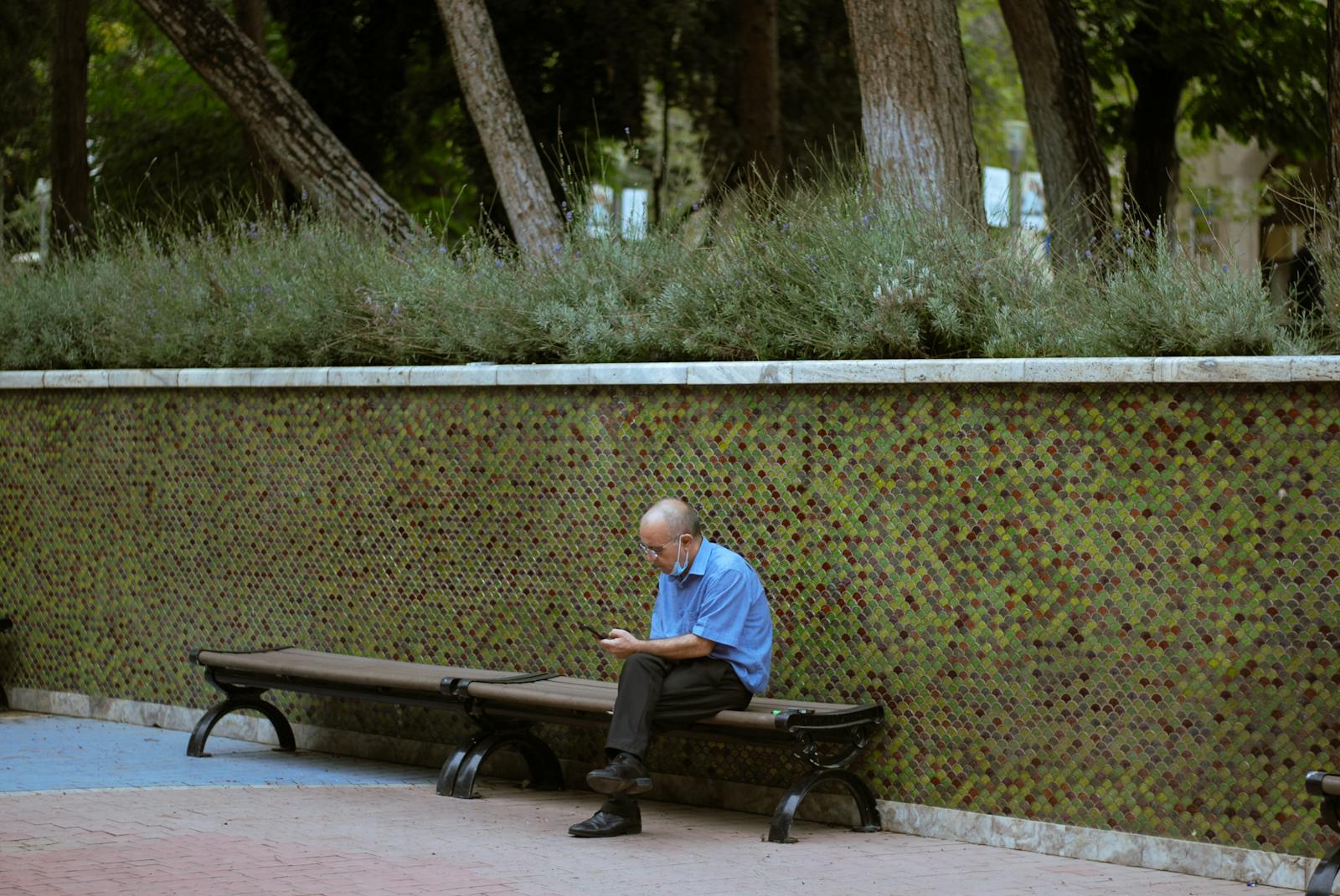 An older man sitting alone on a bench in a park, contemplative and reflective