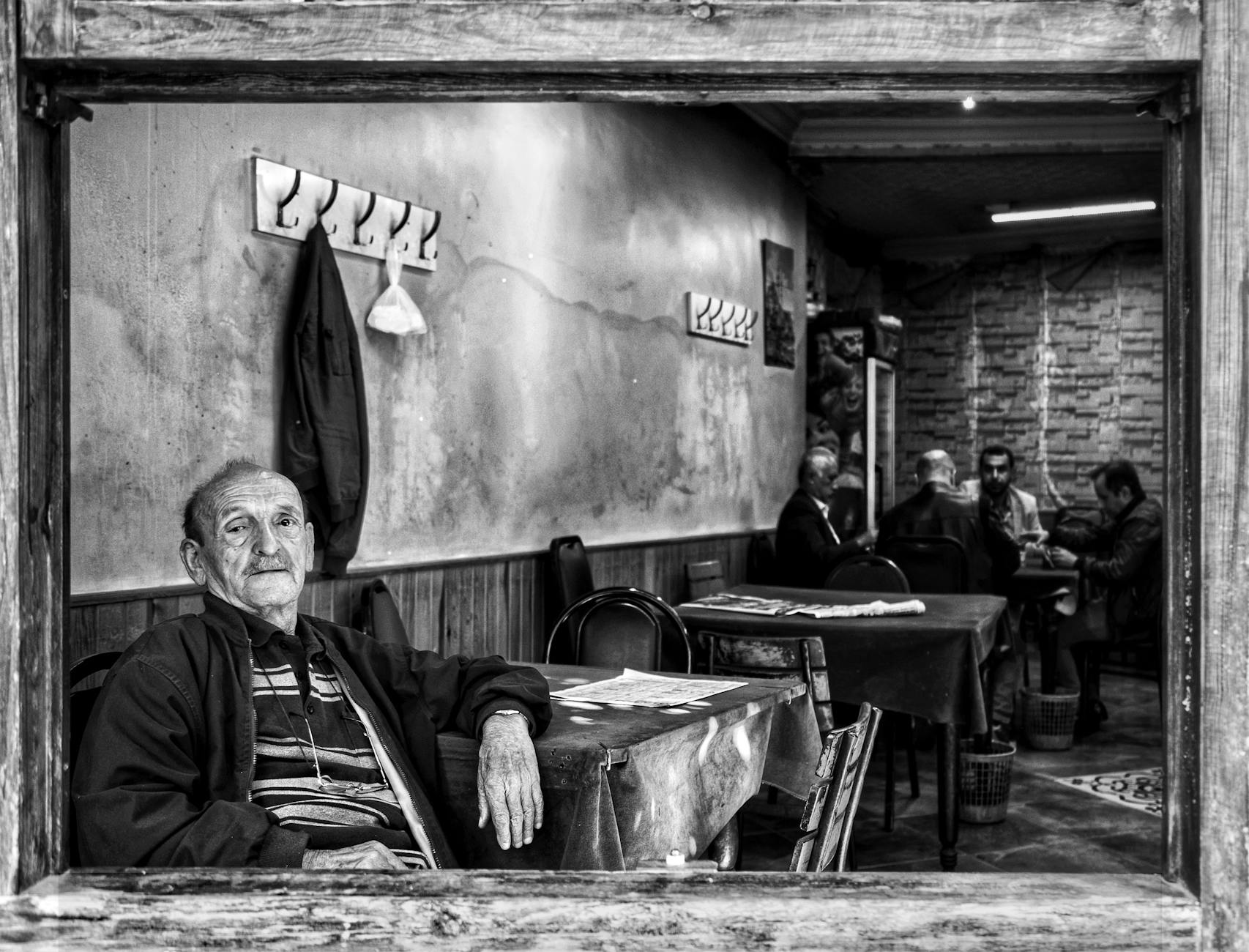Monochrome scene of an elderly man sitting in an Istanbul café.