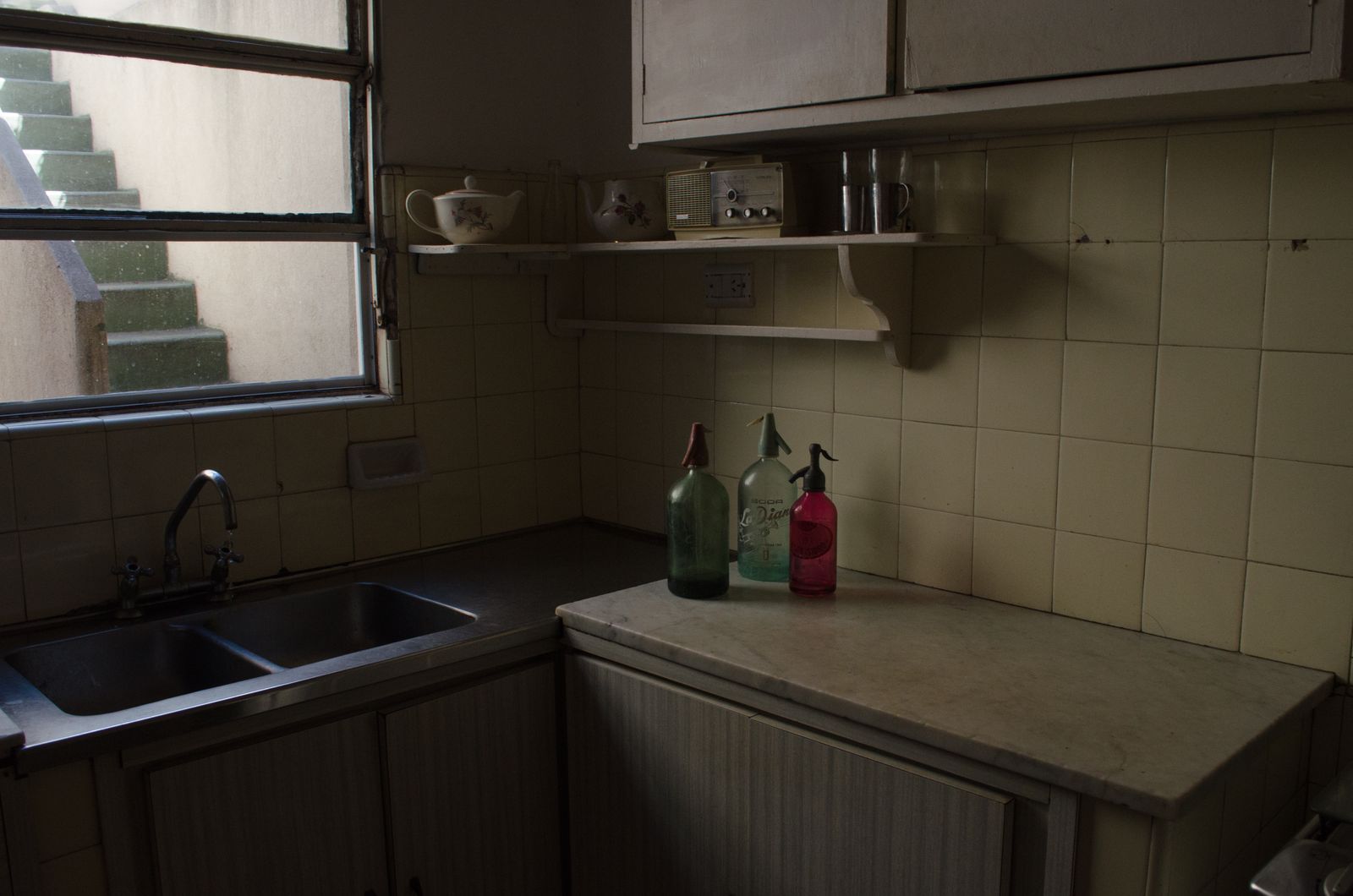 The habit of keeping the radio on in an empty house often has less to do with company than with the memory of a kitchen where a voice in the background meant someone was home and nothing bad was happening yet