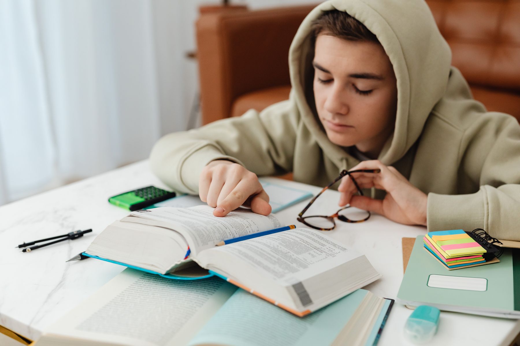 A student studies with books and notes at a table, a representative image illustrating the topic of self-discipline and study habits.