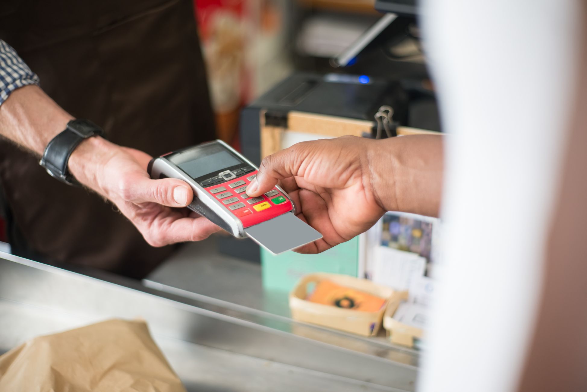 A customer uses a card for a contactless payment at a retail store. Business and consumerism concept.