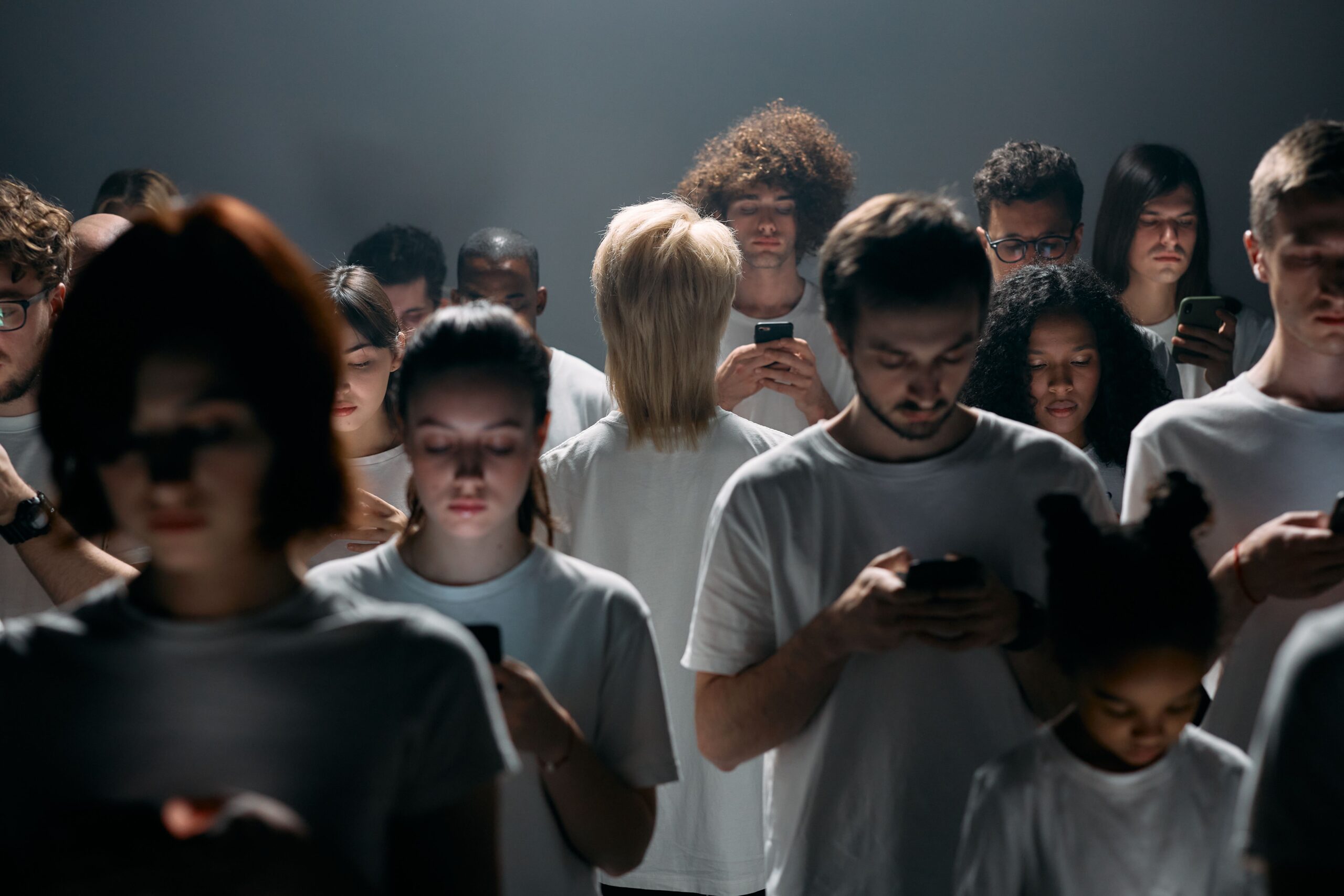 A large group of people standing together while looking at smartphones