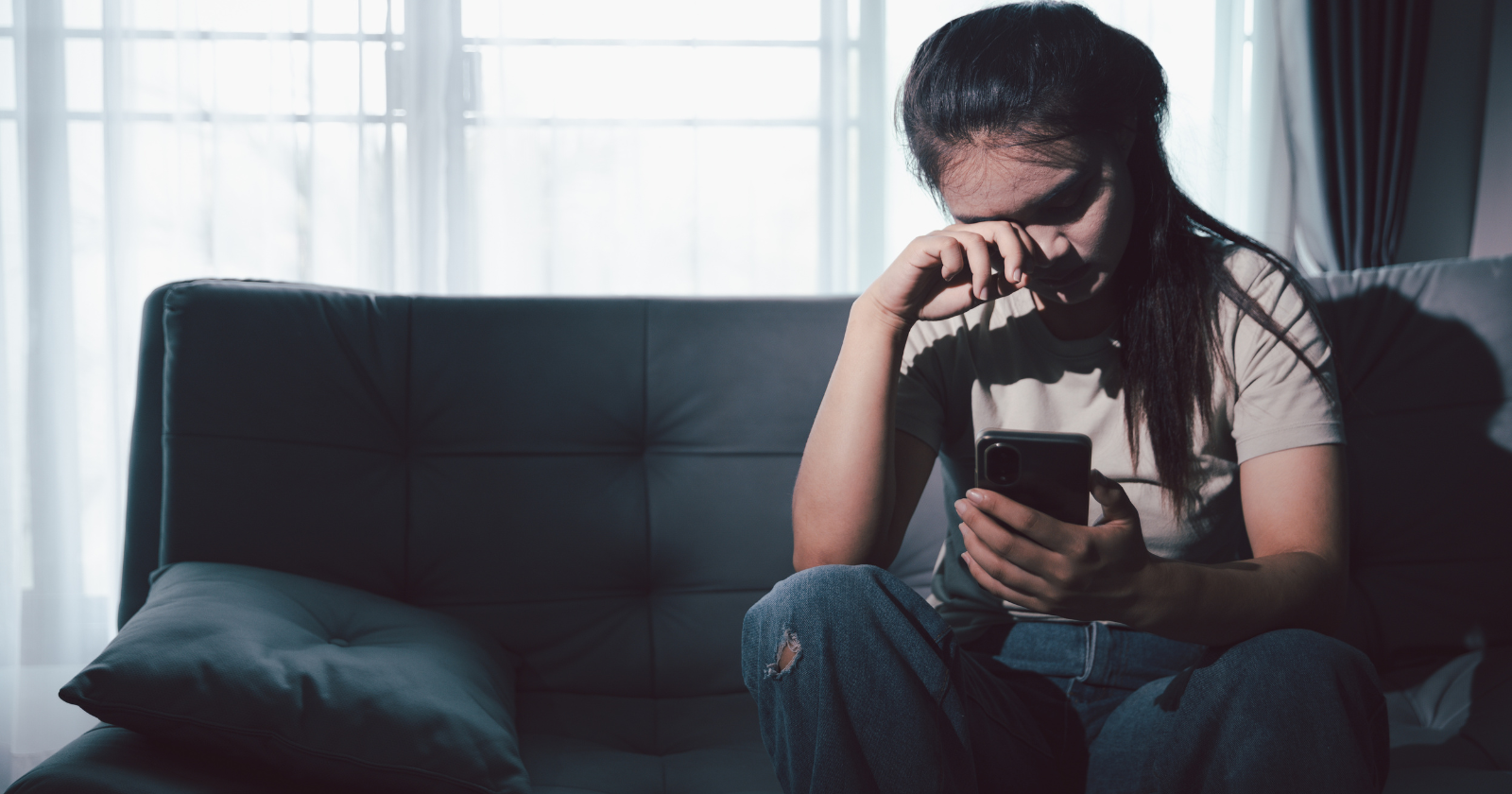 Woman crying while looking at a phone