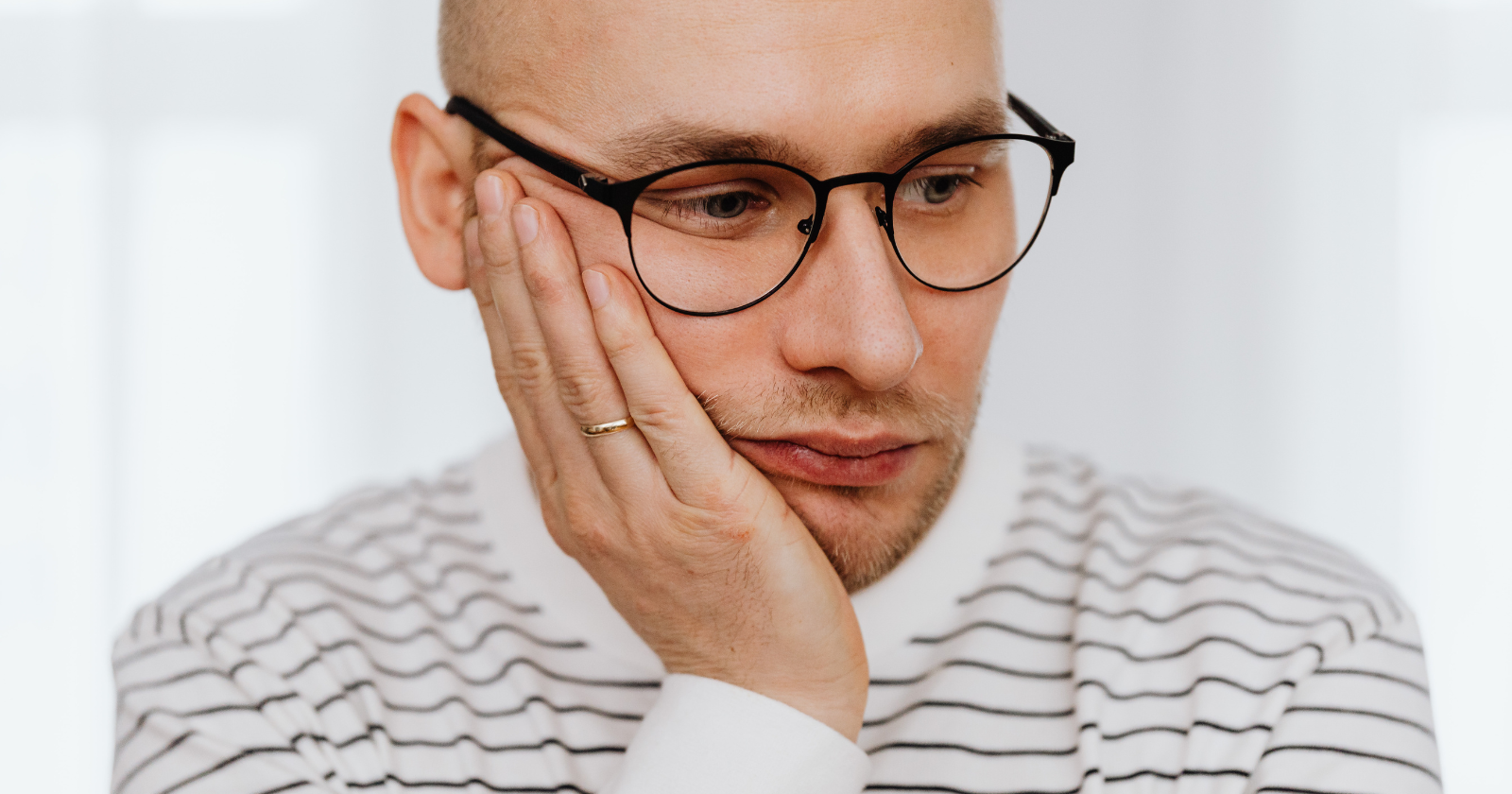 Thoughtful man with glasses resting his hand on his cheek