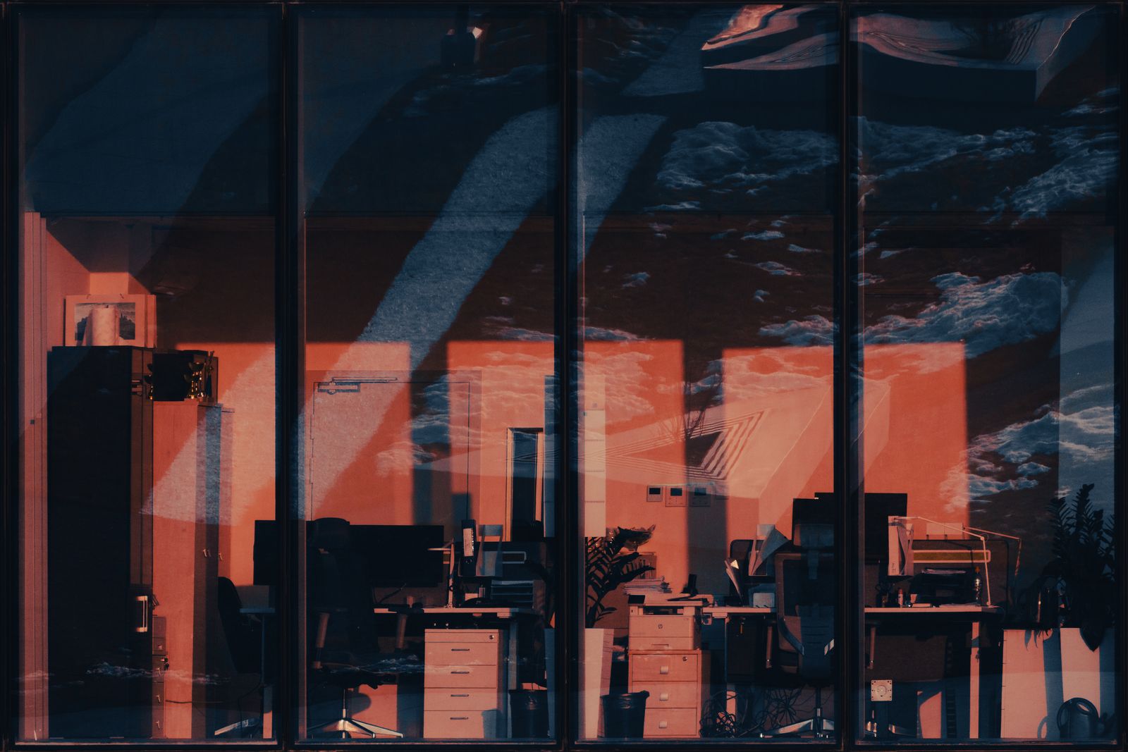 An empty office interior at dusk with the city visible through large windows.