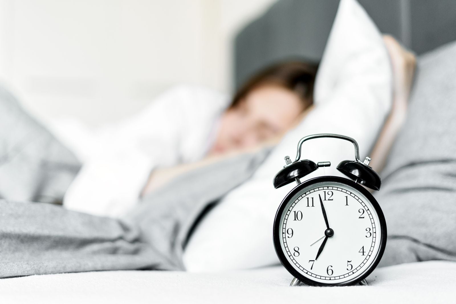 A retro alarm clock beside a sleeping person