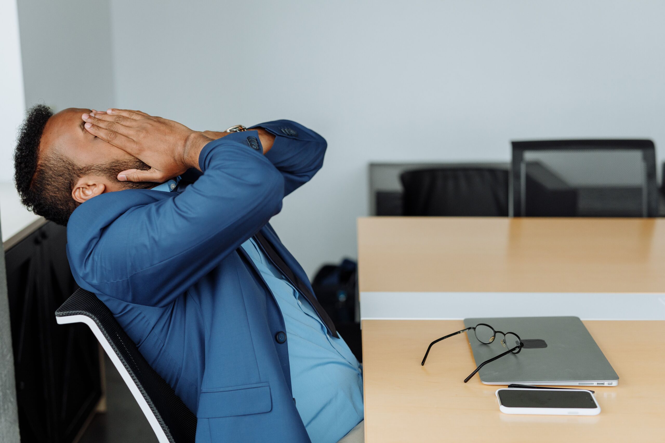 A stressed professional covering his face while seated at an office desk