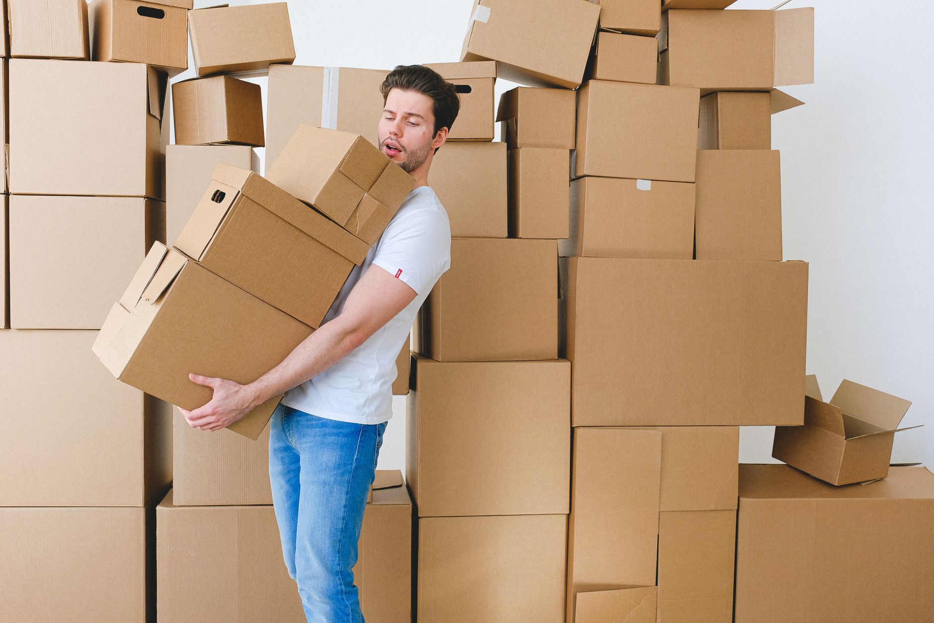 A person struggling to carry a large stack of boxes alone