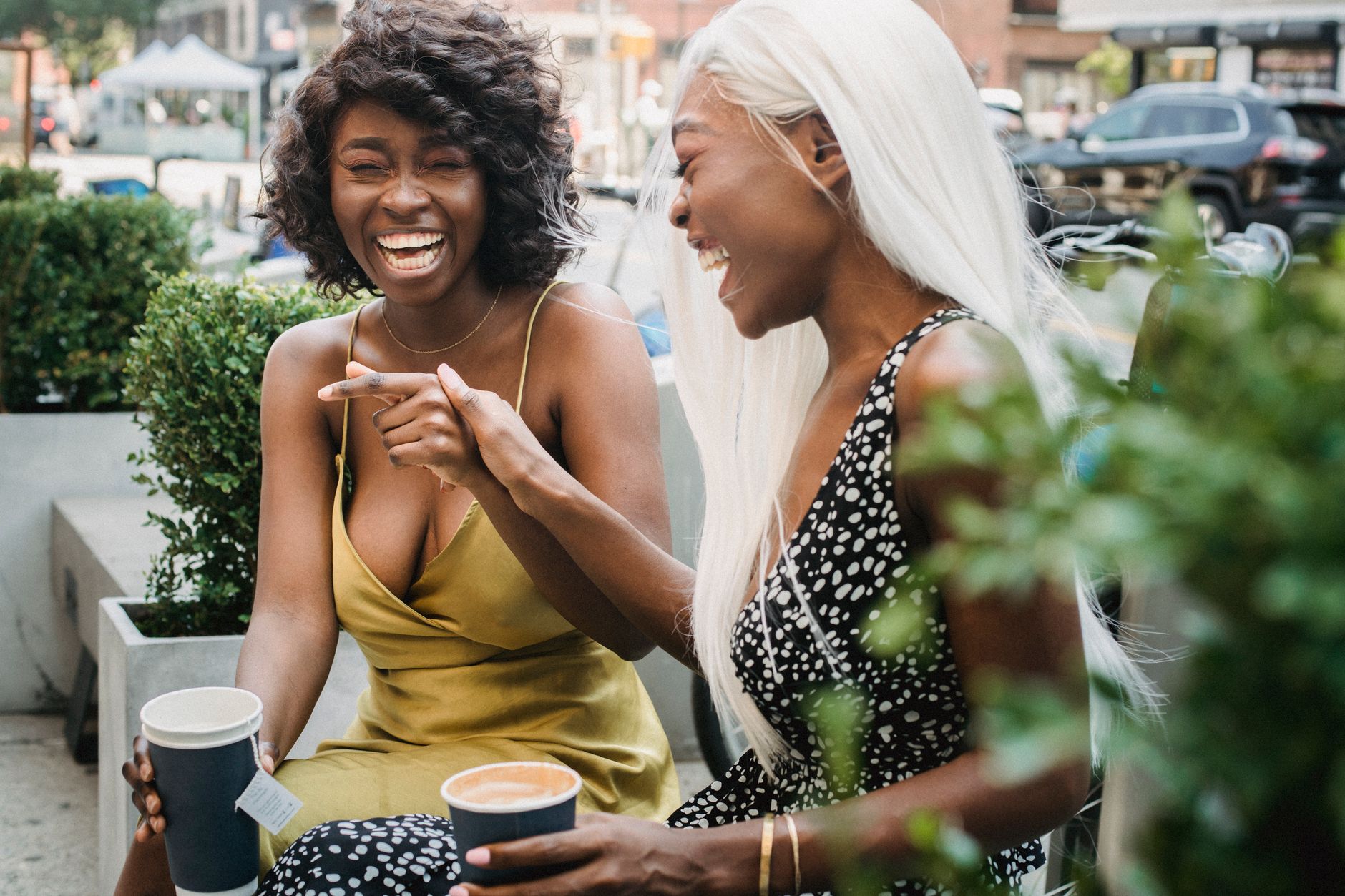 Two friends leaning towards each other and laughing during a conversation