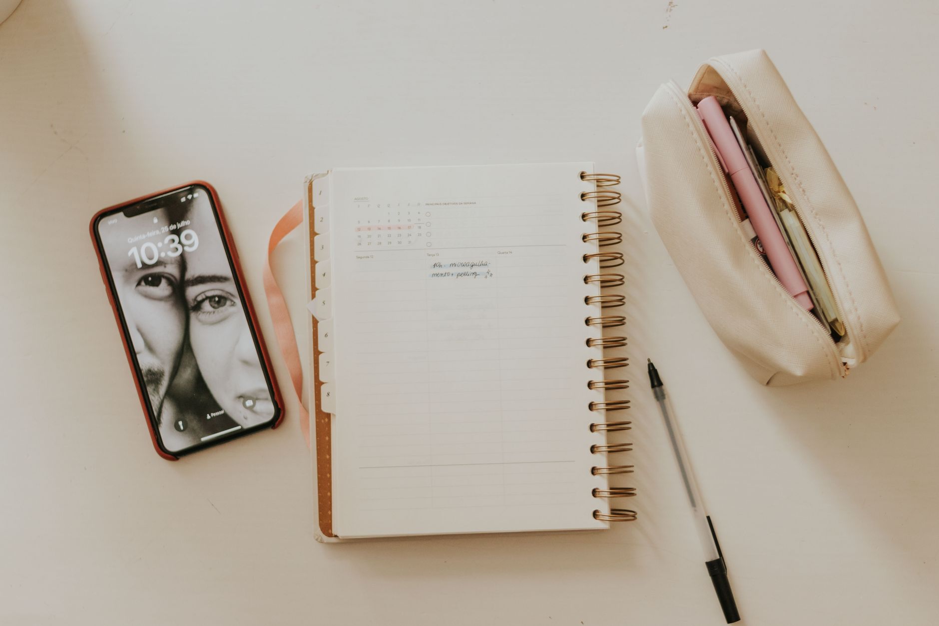 An organized desk with an open planner, smartphone and stationery