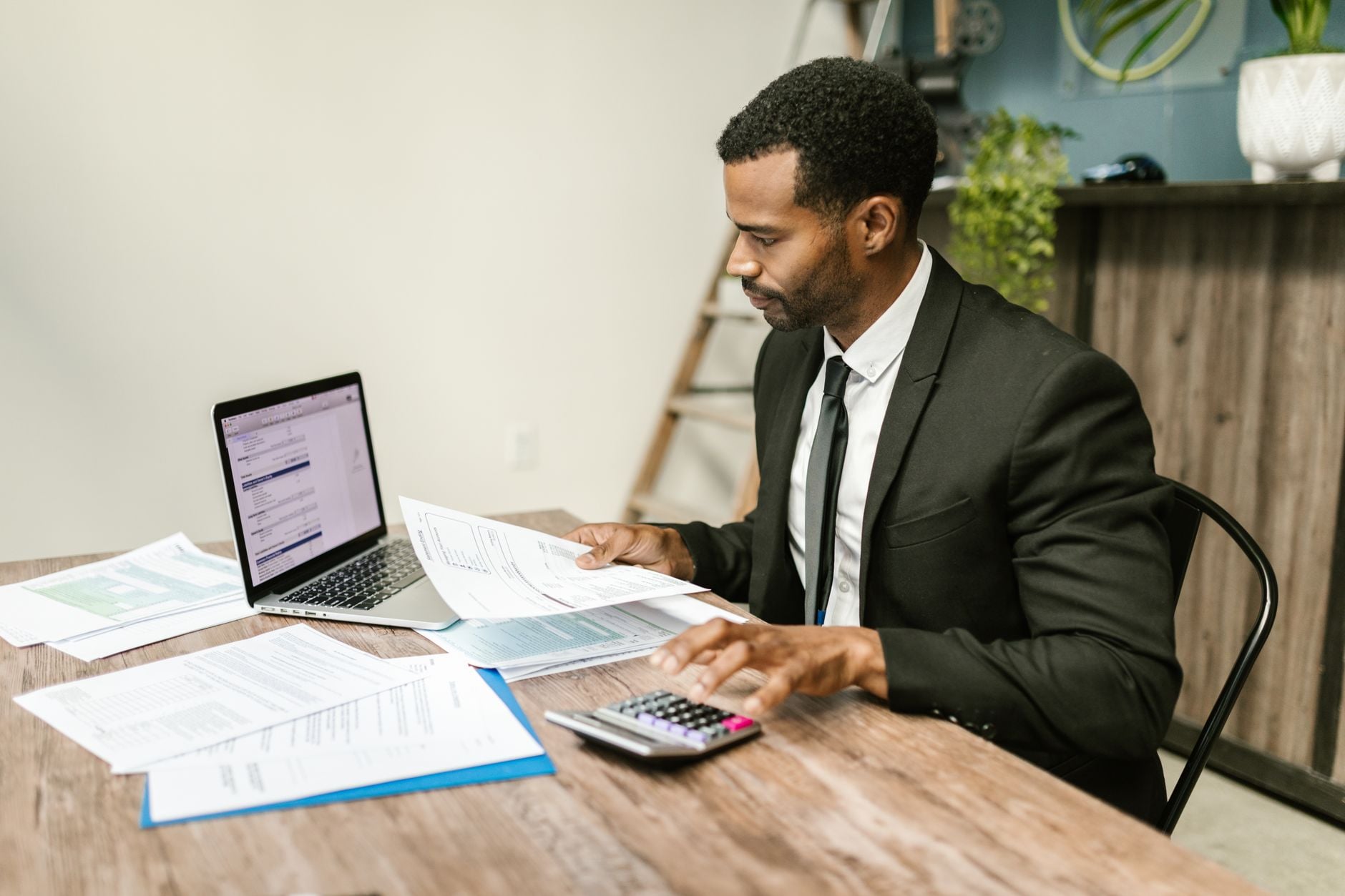 A businessman reviewing financial documents with a calculator and laptop
