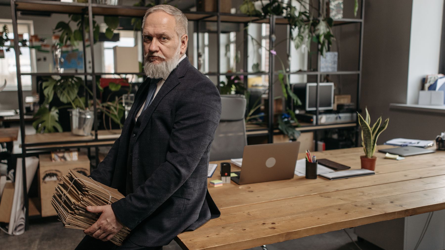 An older professional holding folders in a modern office