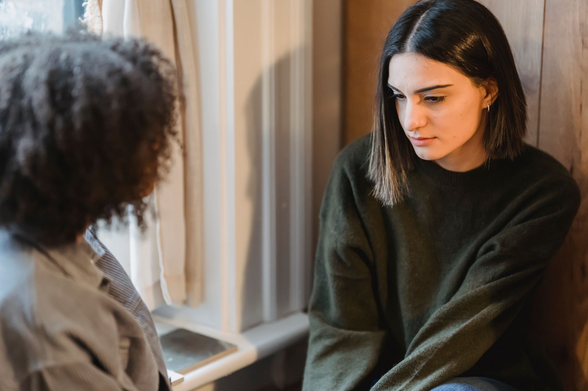 Two friends having a serious conversation beside a window