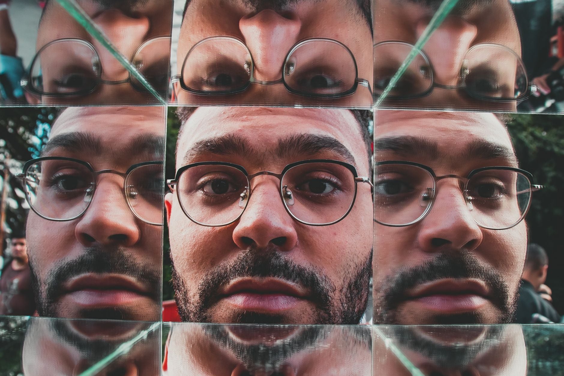 A man's face repeated across multiple mirrored reflections
