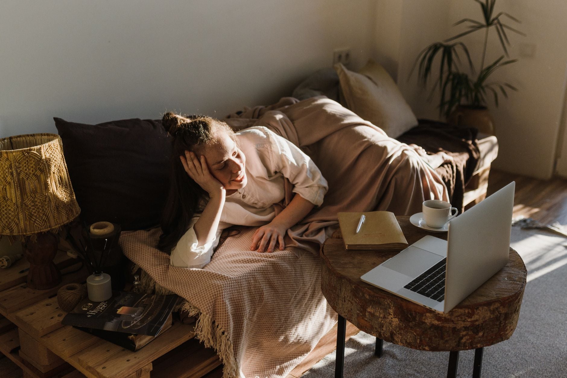A person rests on a sofa while a laptop sits open on a nearby table