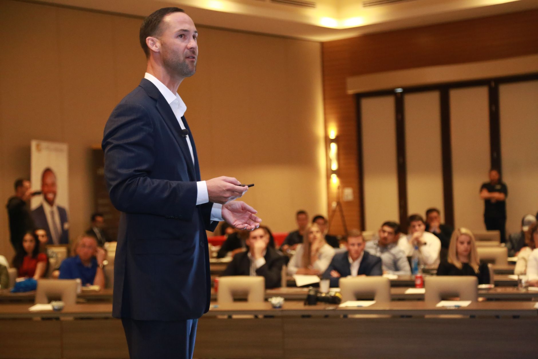 A conference speaker gesturing with both hands while addressing an audience