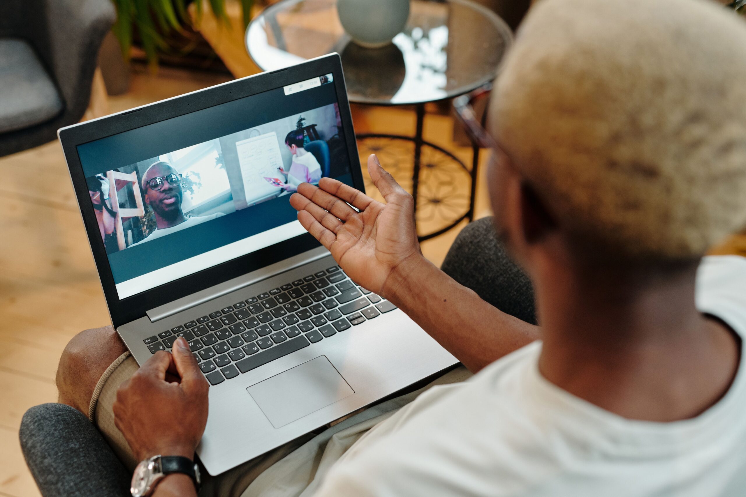 Person gesturing toward a laptop screen during a face-to-face video call