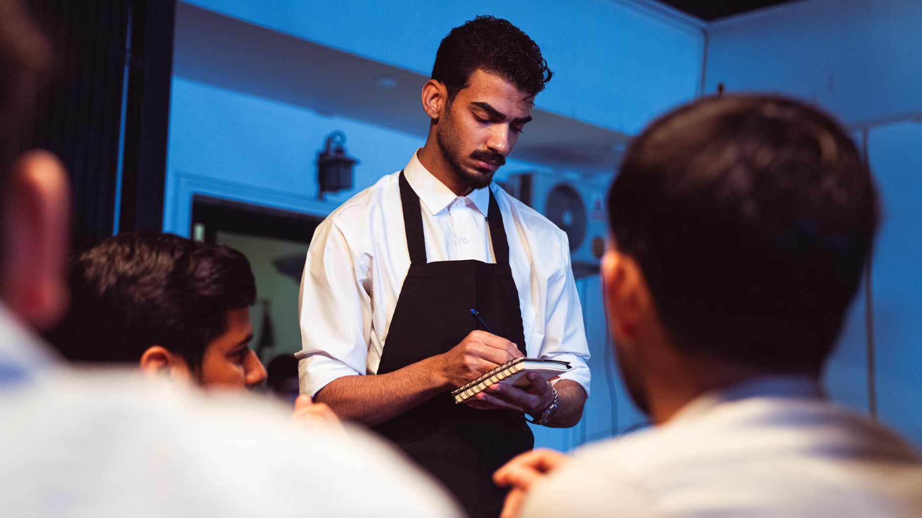 A waiter writing down a customer's order at a restaurant table
