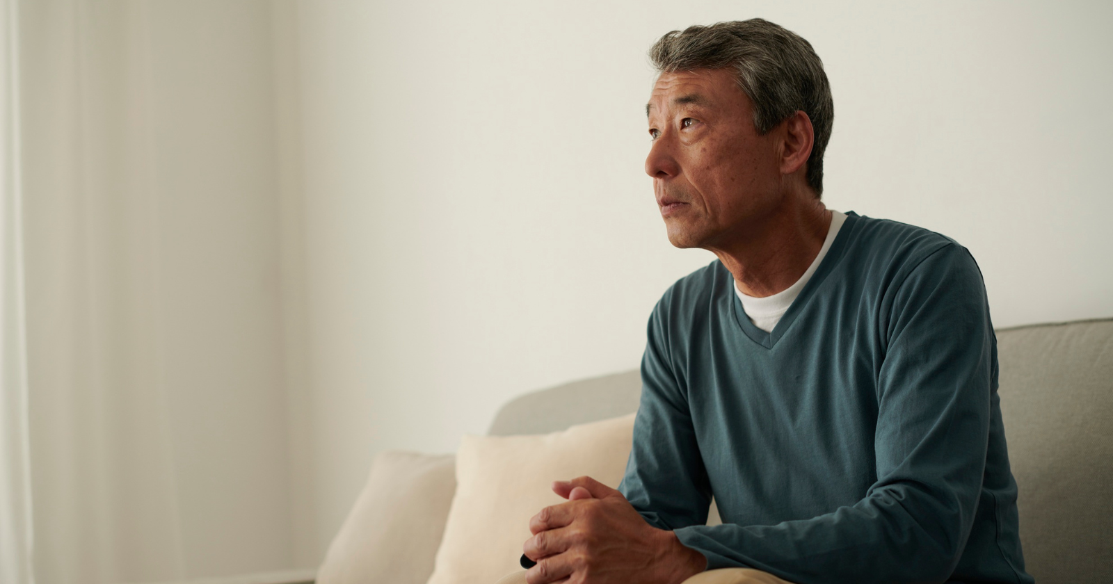 Older man sitting indoors and looking away