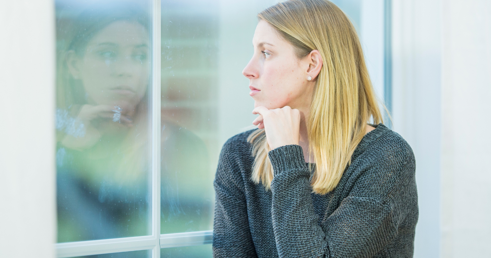 Woman sitting beside a glass wall and looking away