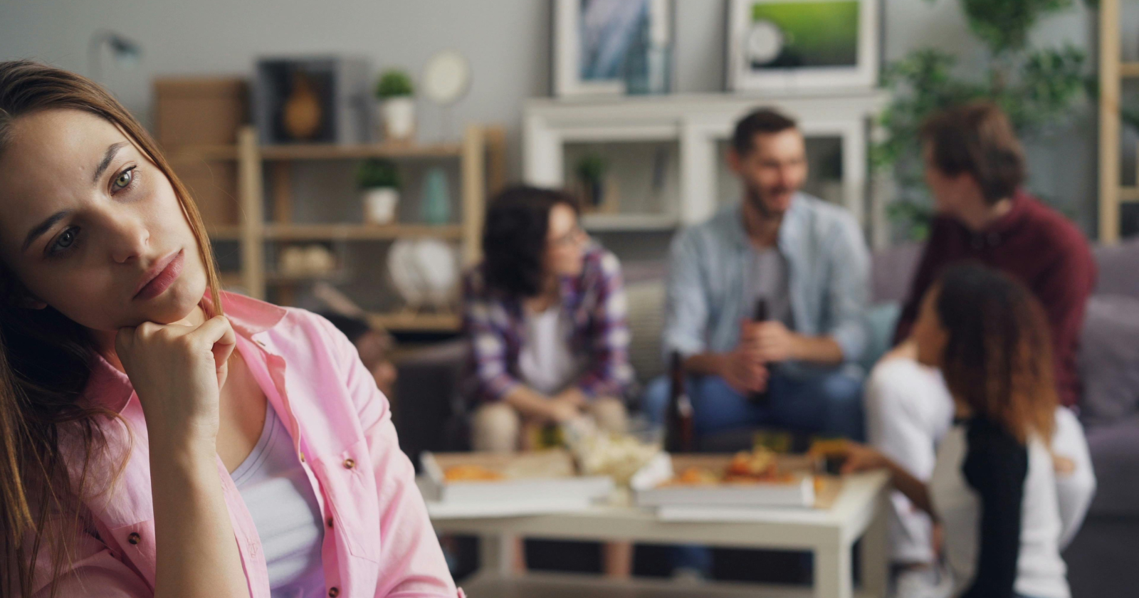 Woman apart from a group socialising behind her