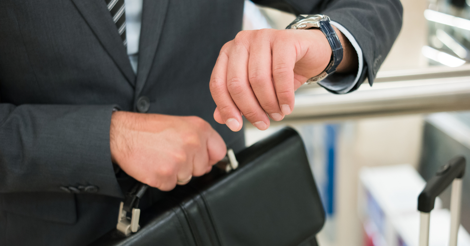 Suited commuter checking his wristwatch while holding a briefcase