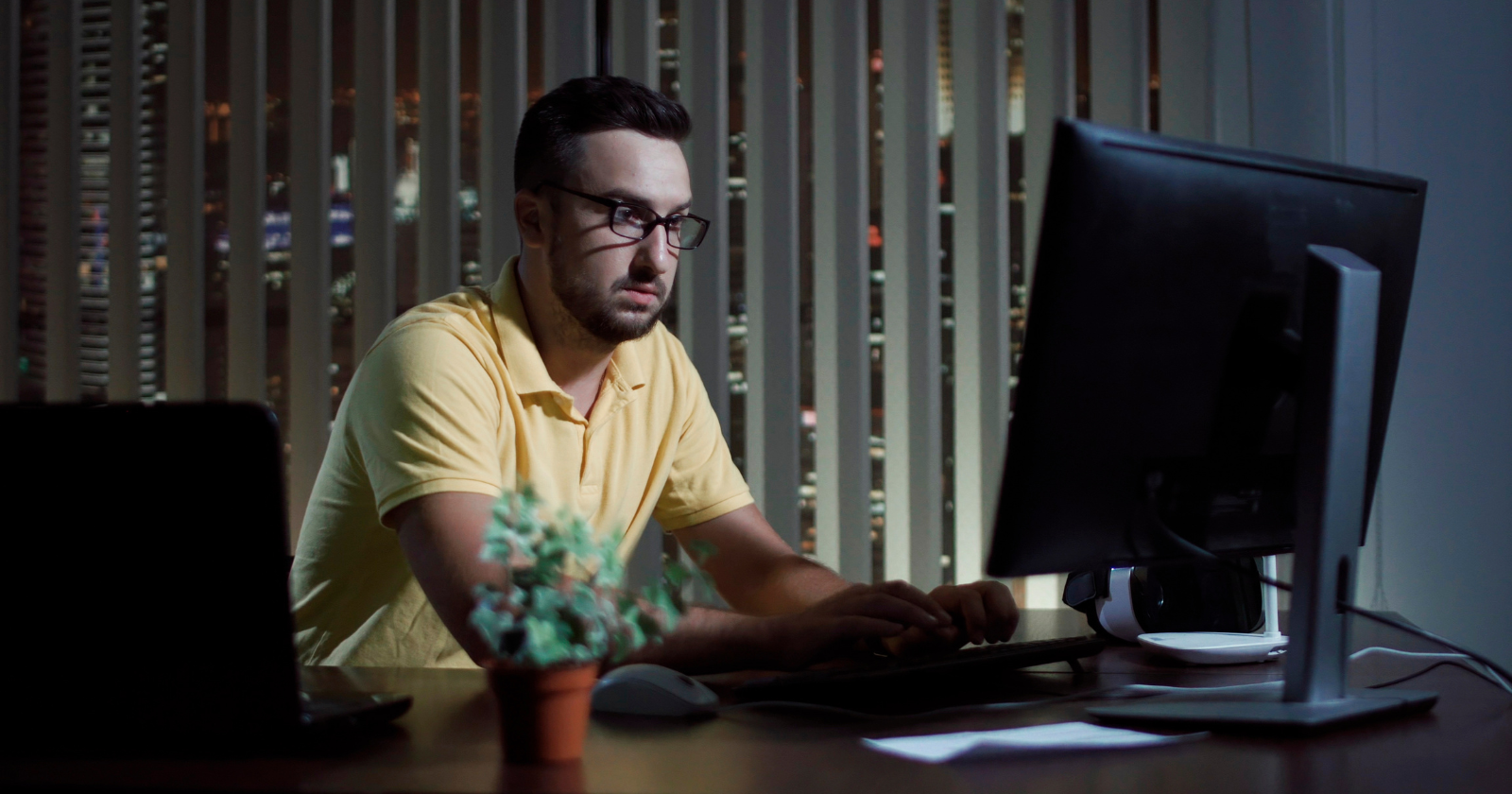 Man working at a desktop computer in a dimly lit room