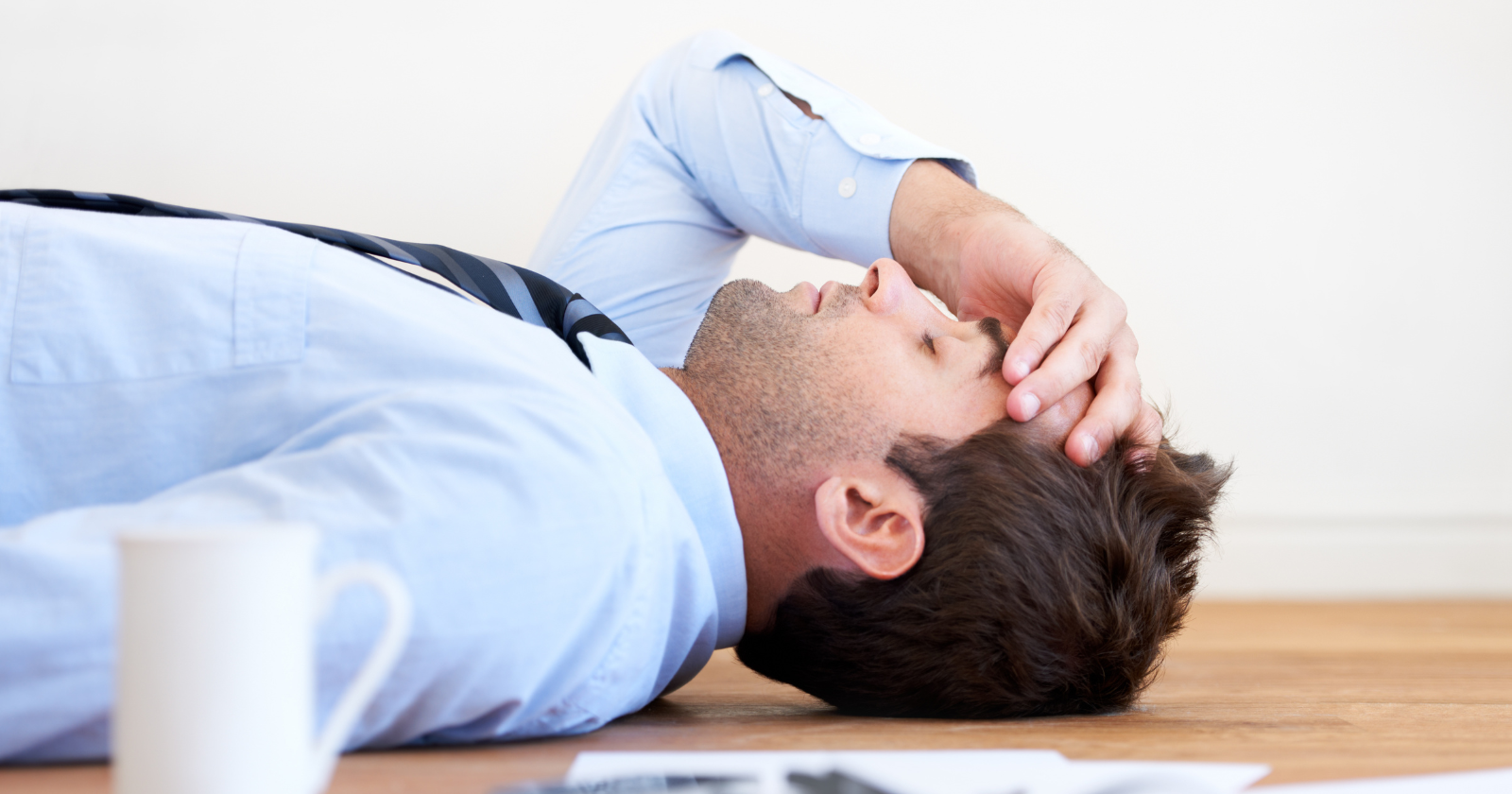 Man lying on the floor with his hand on his forehead
