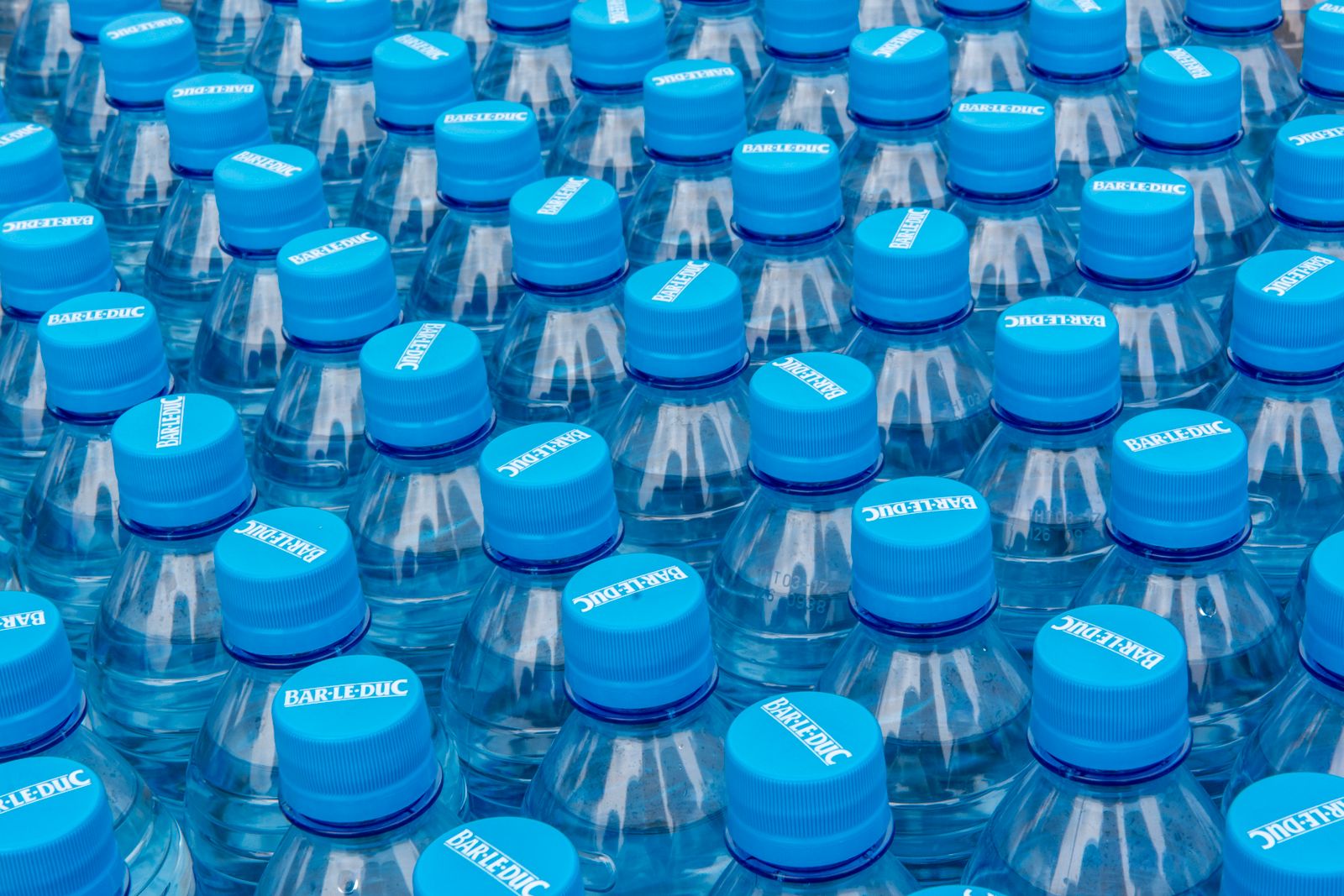Stacked clear plastic water bottles with blue caps.