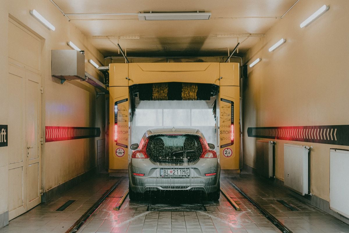 A silver car covered in suds inside an automated car wash