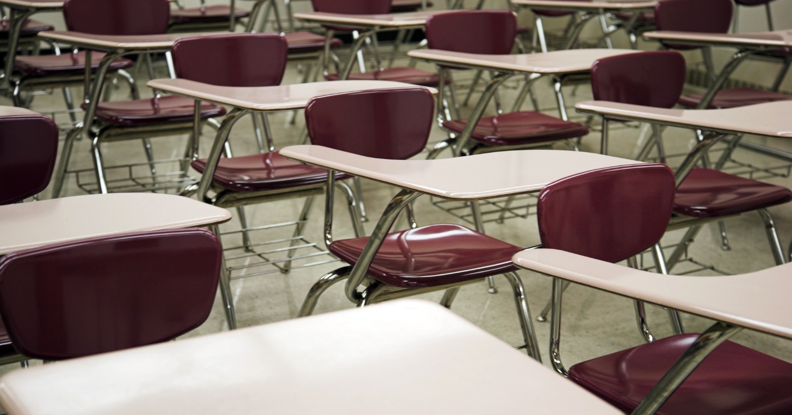 Rows of empty tablet-arm desks in a university classroom