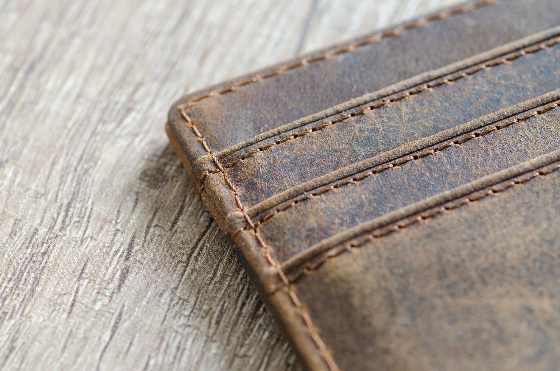 Brown leather wallet lying open on a wooden surface