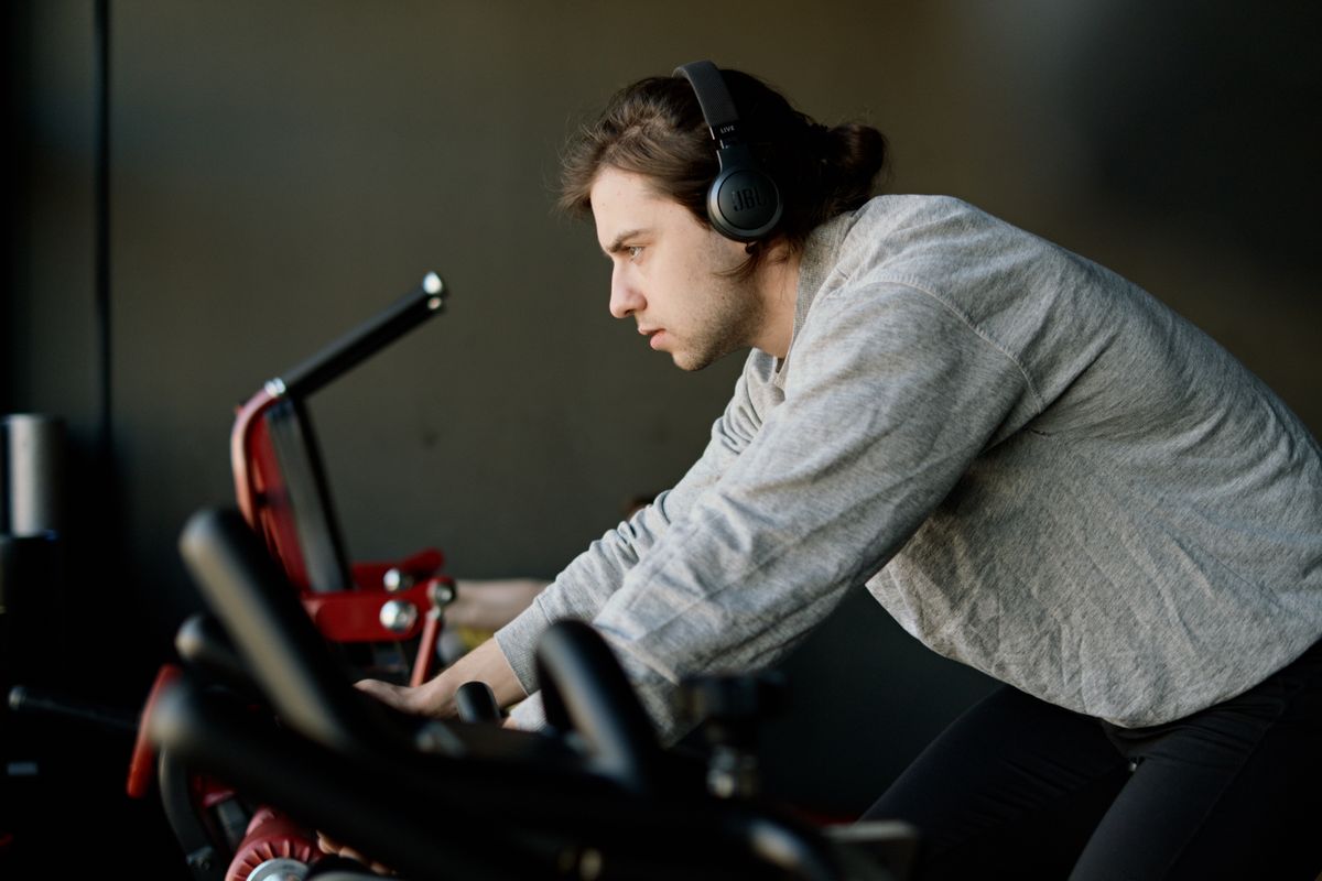A man wearing headphones while exercising on a stationary bike