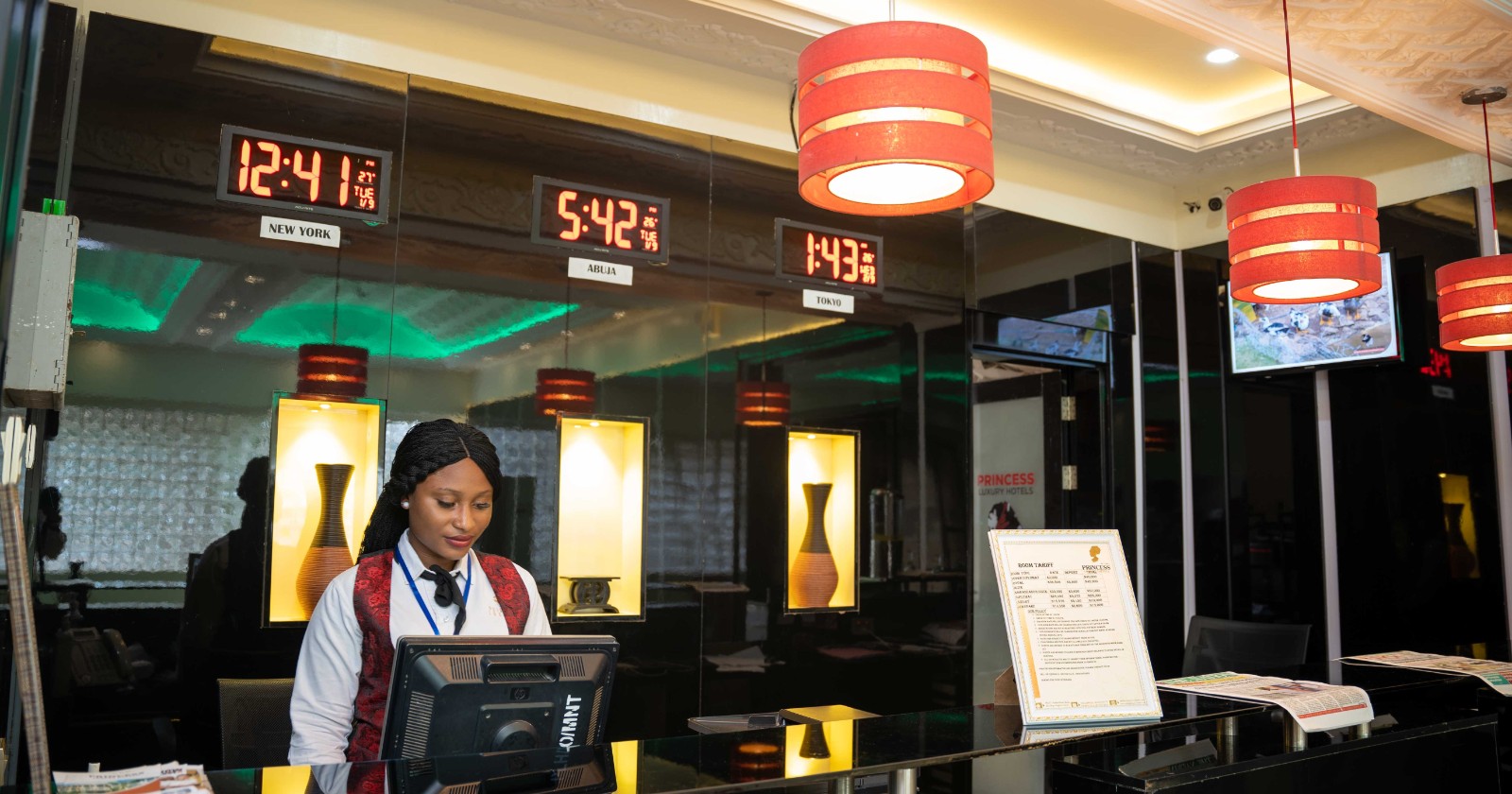 Two uniformed receptionists standing side by side behind a hotel front desk