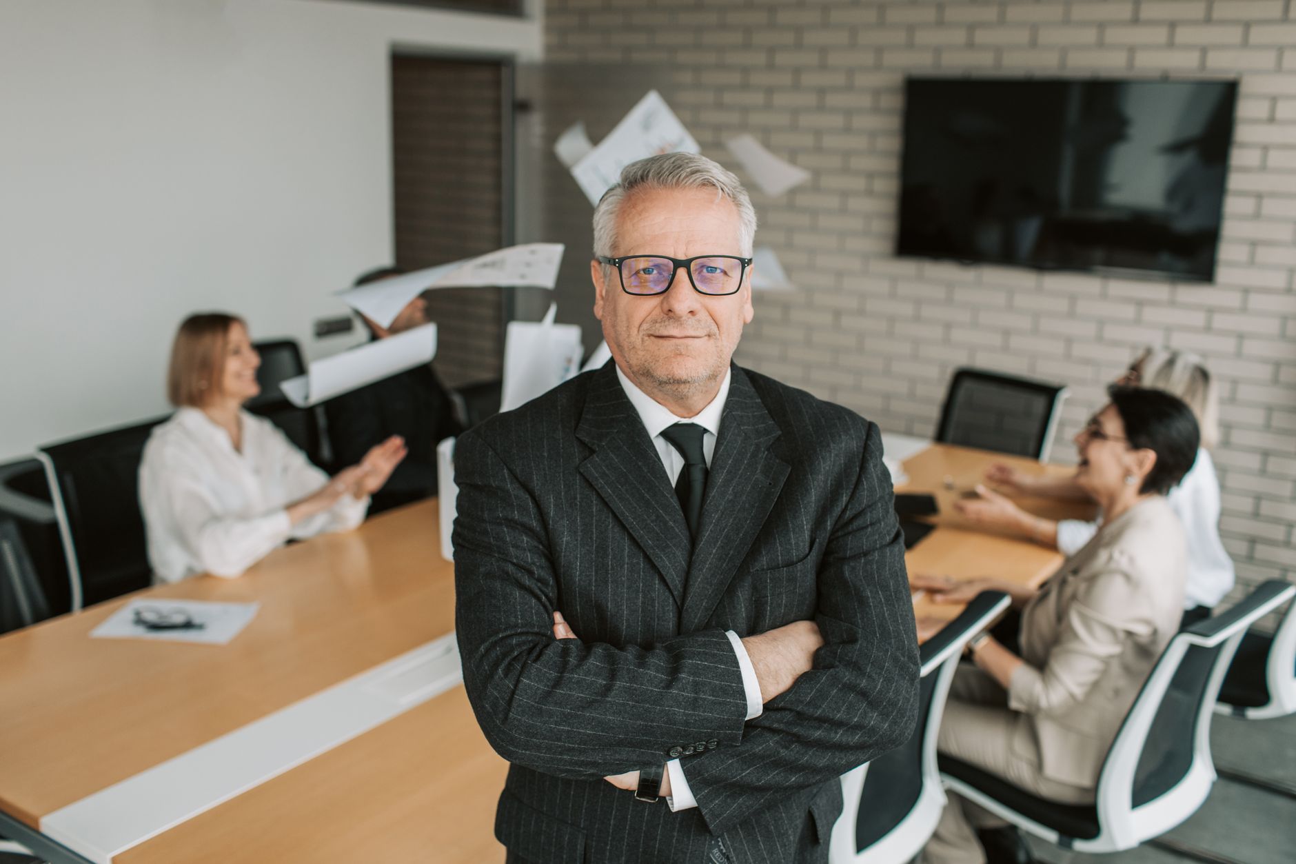 Older executive standing with folded arms in an office