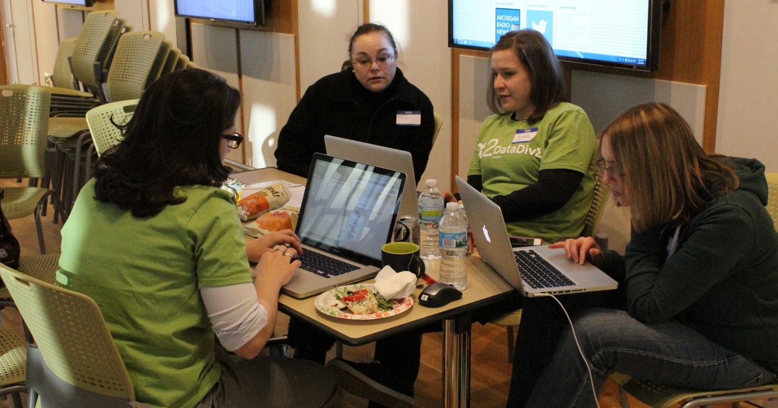 Four adults working together around laptops at a community volunteer event