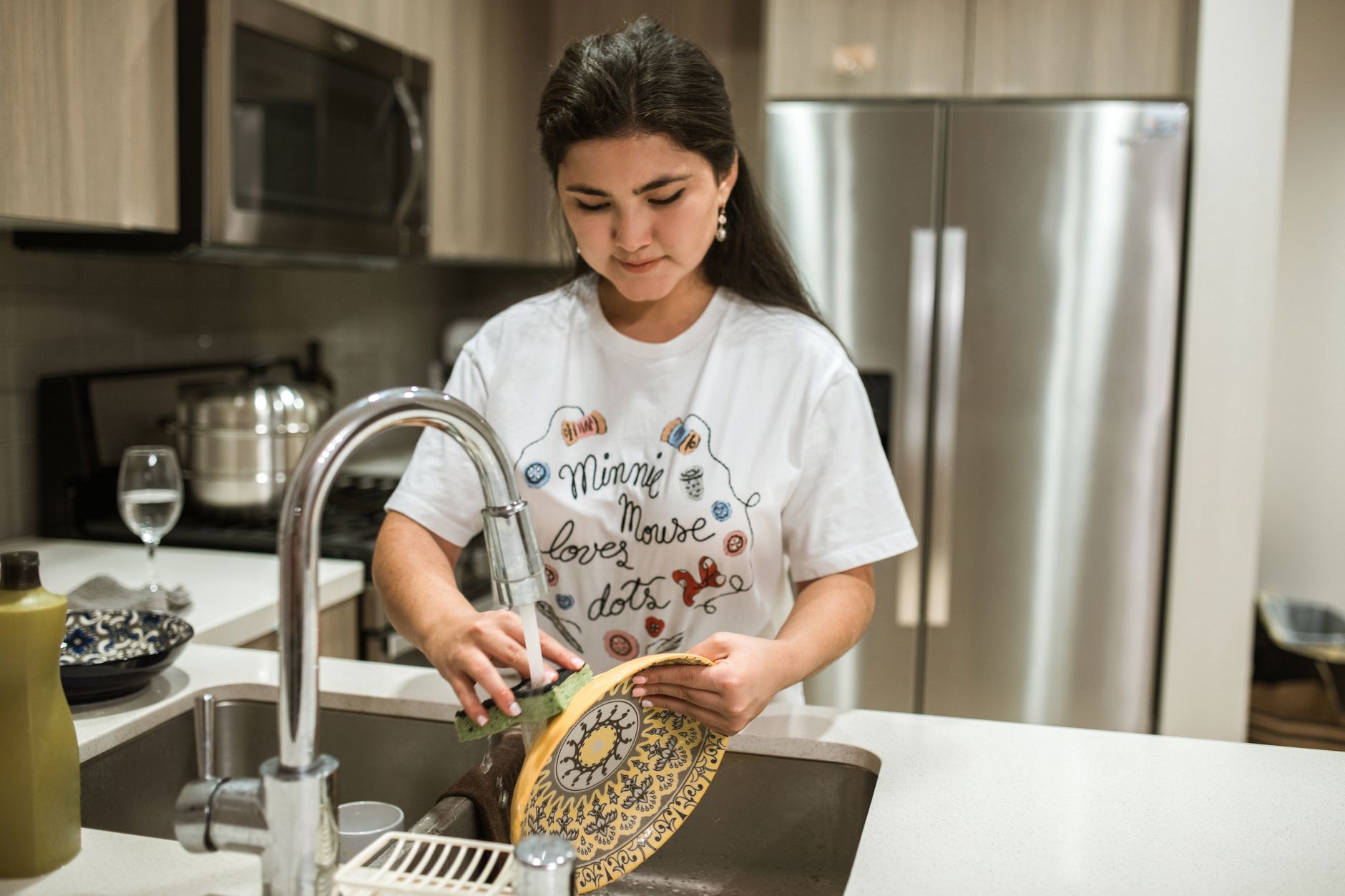 Woman washing a plate at a modern kitchen sink
